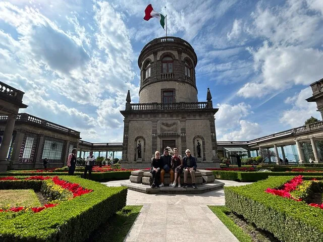 Eine Gruppe von Menschen, die an einem Brunnen im Innenhof von Schloss Chapultepec sitzt.