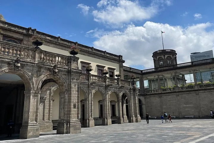 Der Außenhof des Schlosses Chapultepec mit Steinbögen und einem Turm.